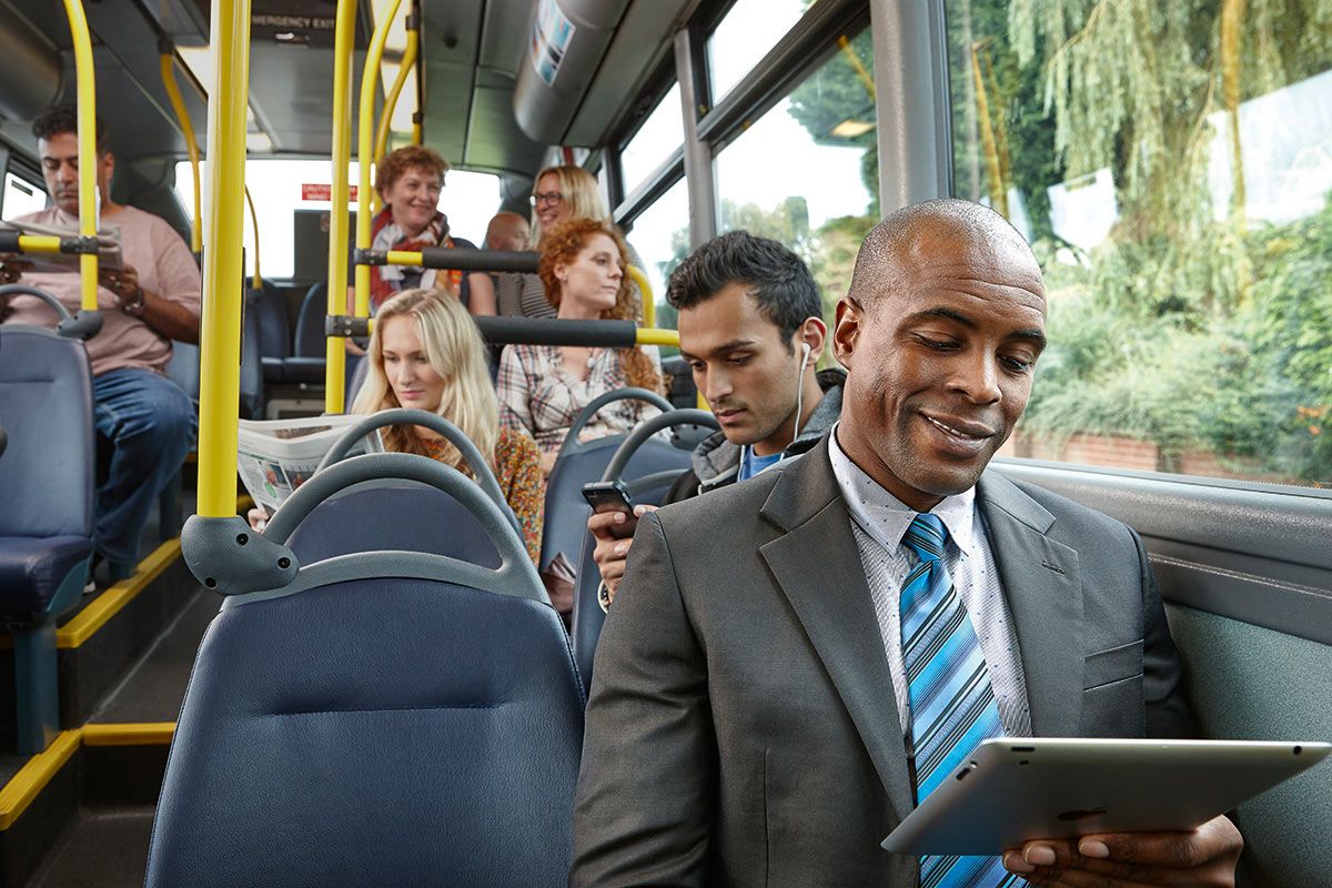 Bus passengers on an Arriva bus showing a man on his ipad