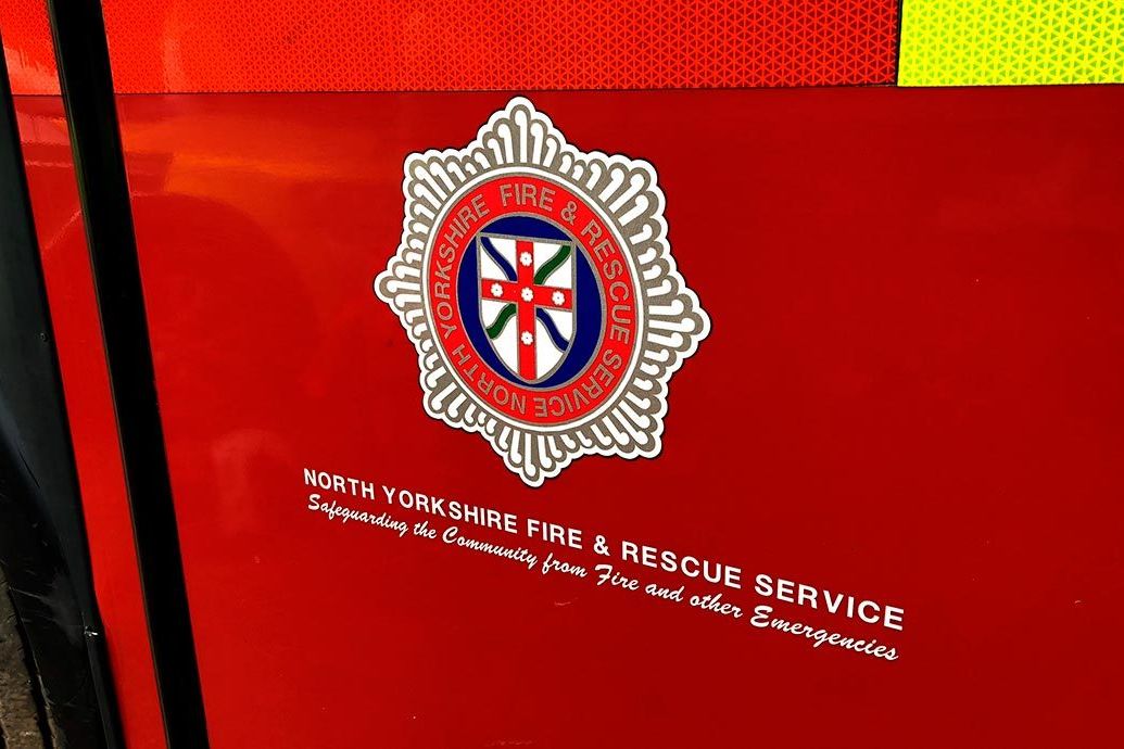 North Yorkshire Fire and Rescue Service badge logo on the side of a red fire engine